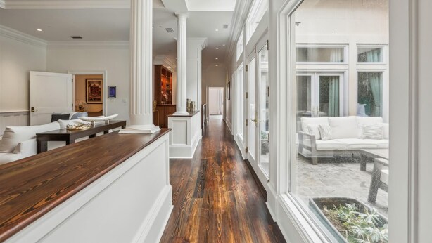 A spacious hallway with a wooden floor, white walls, and large windows offering a view of the outdoors. - NEW REMODEL Packard at the Historic Bryson Building (Savannah)