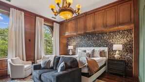 A bedroom with a large bed, two bedside tables, a sofa, and a chandelier. - NEW REMODEL Packard at the Historic Bryson Building (Savannah)