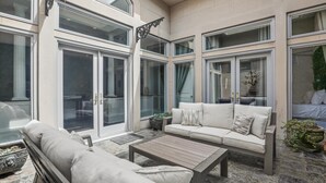 A sunlit patio with a sofa, a wooden table, and a bench. - NEW REMODEL Packard at the Historic Bryson Building (Savannah)