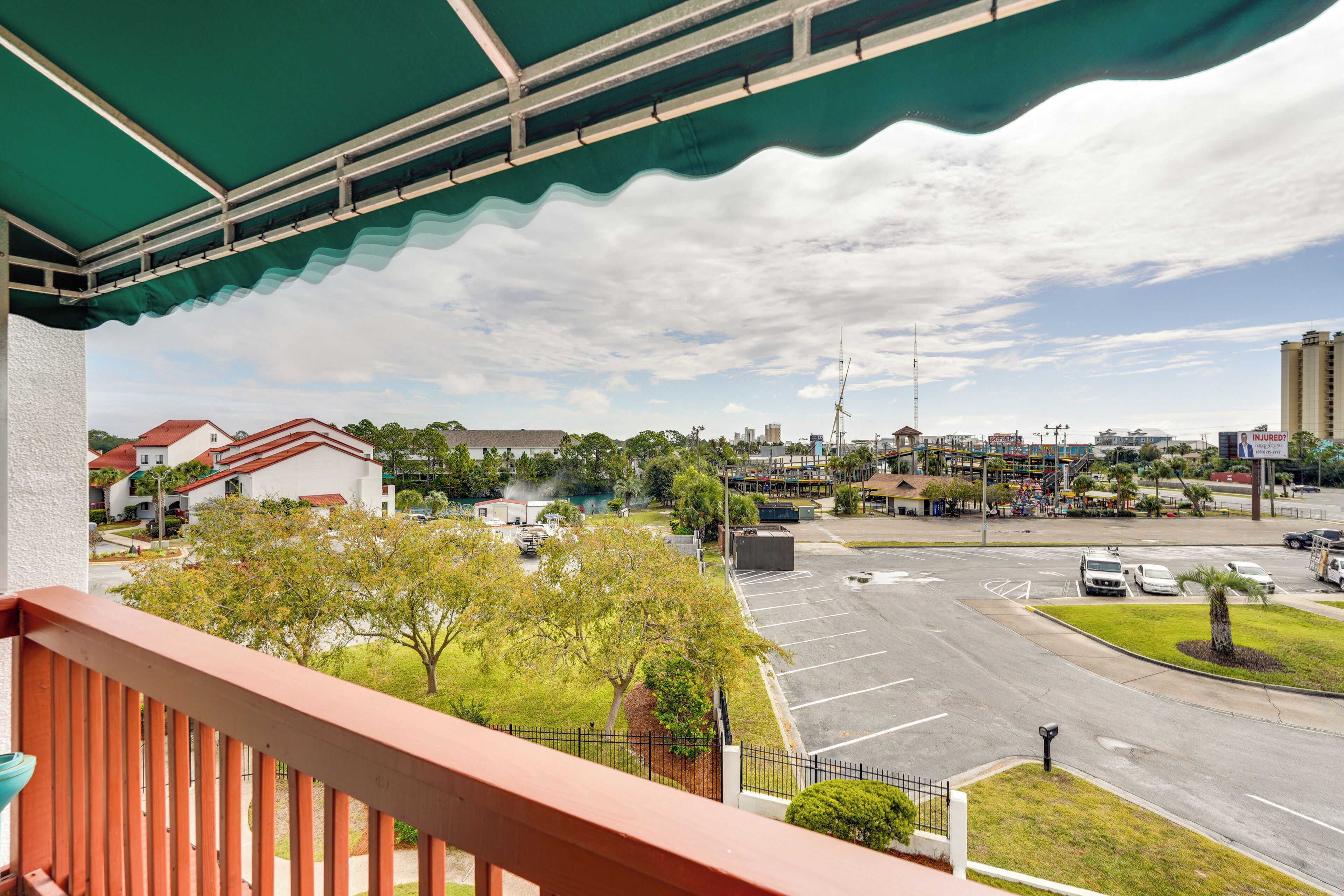 Vista desde un balcón sobre un estacionamiento y un paisaje urbano con edificios y árboles.