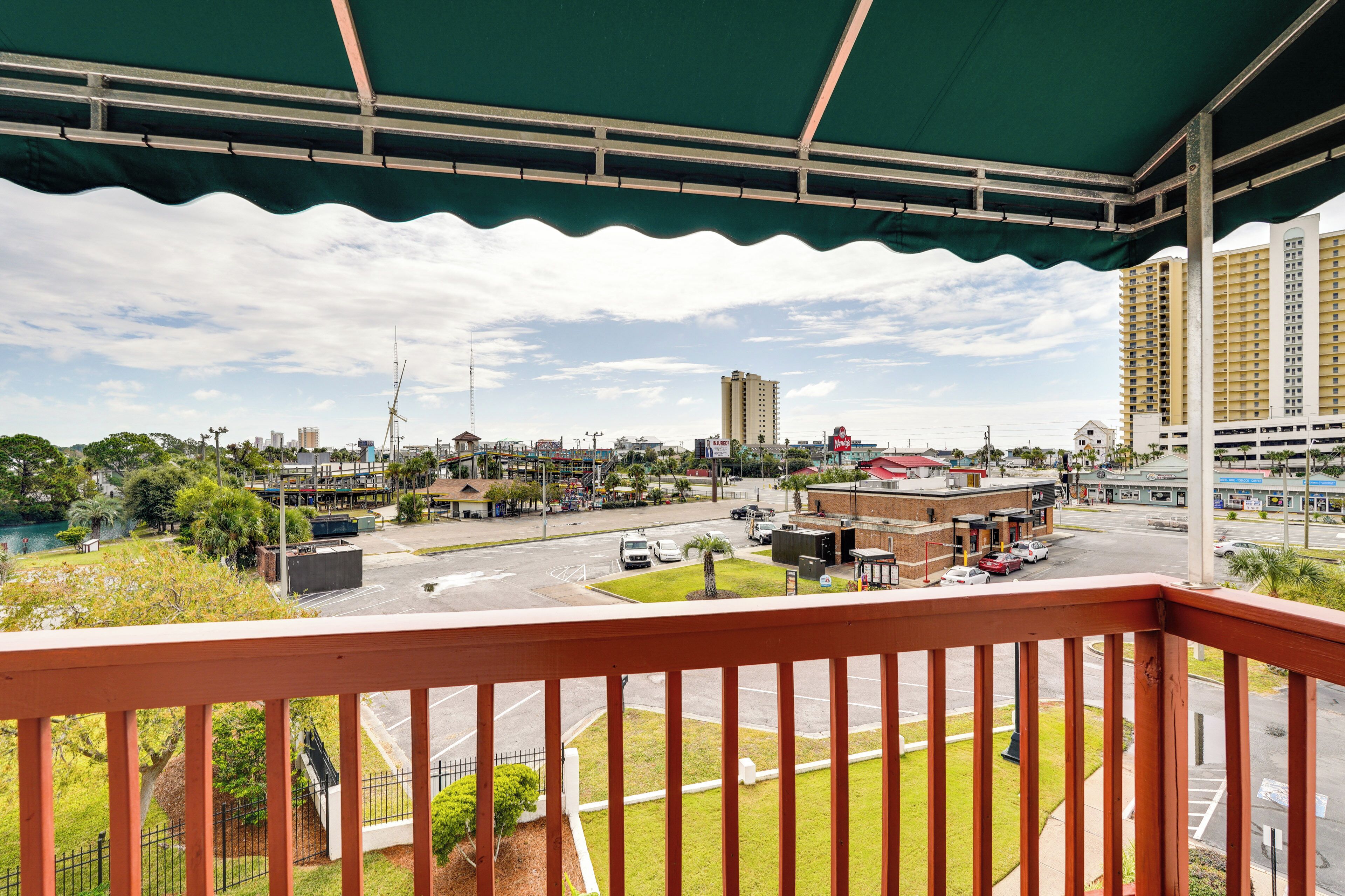 A balcony with a view of a cityscape, including buildings, a parking lot, and a road.