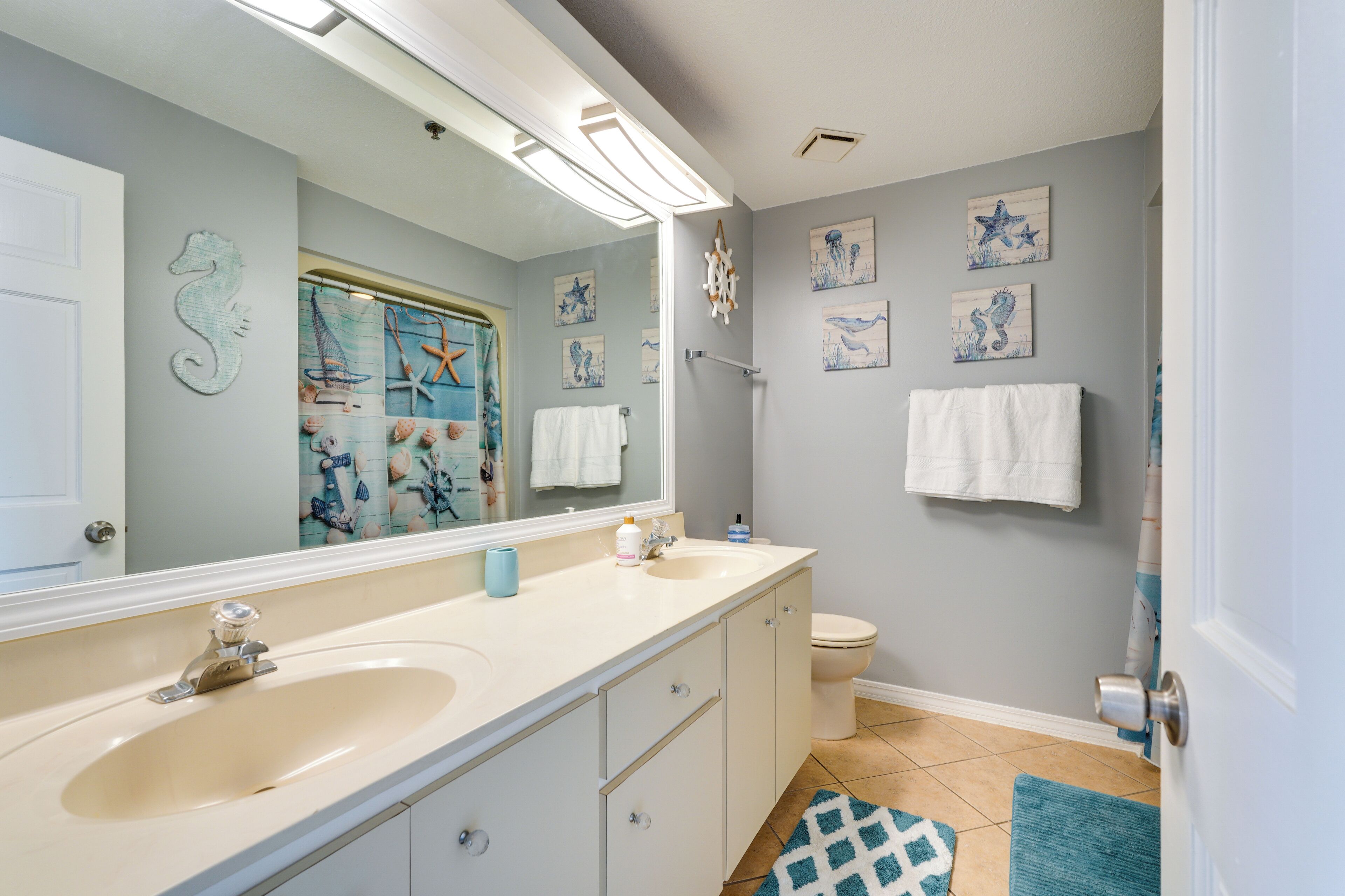 A bathroom with a double sink vanity, a large mirror, and a shower area.