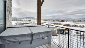 A balcony with a view of a snowy landscape, including mountains and industrial buildings. - Winter Park Retreat: Balcony, Hot Tub & Fireplace! (Fraser)