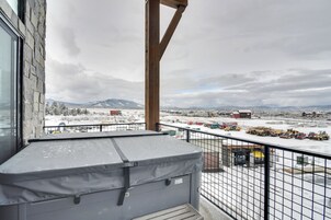 Un balcón con vistas a un paisaje nevado, que incluye montañas y edificios industriales.