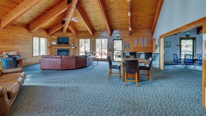 Un chalet spacieux avec un plafond haut, une cheminée, un coin repas et une grande fenêtre.