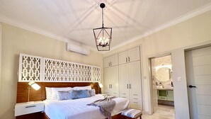 Ein helles Schlafzimmer mit einem hölzernen Bett, Nachttischlampen, einem dekorativen Kopfteil und einem großen Kleiderschrank.