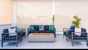 Ein moderner Außenbereich mit einer Couch und zwei Sesseln, einem Couchtisch und einem großen Fenster mit Blick auf die Stadt.