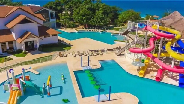 Ein Resort mit großem Pool, Wasserrutschen und Blick auf den Ozean.