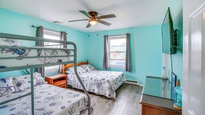 A room with bunk beds, a ceiling fan, a wooden dresser, and a window with curtains. - Beach House w/ Private Pool in North Wildwood (North Wildwood)
