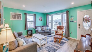 A living room with teal walls, a grey sofa, a white coffee table, and a patterned armchair. - Beach House w/ Private Pool in North Wildwood (North Wildwood)