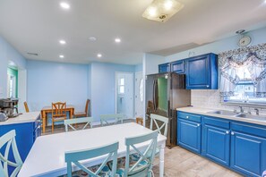 Una cocina con armarios azules, encimera blanca y refrigerador de acero inoxidable.