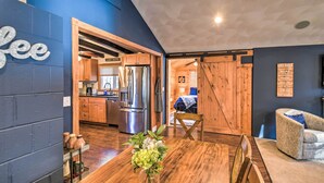 A modern kitchen with wooden cabinets and stainless steel appliances. There is a dining area with a wooden table and chairs.