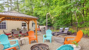 An outdoor patio area with Adirondack chairs, a fire pit, and a covered seating area.