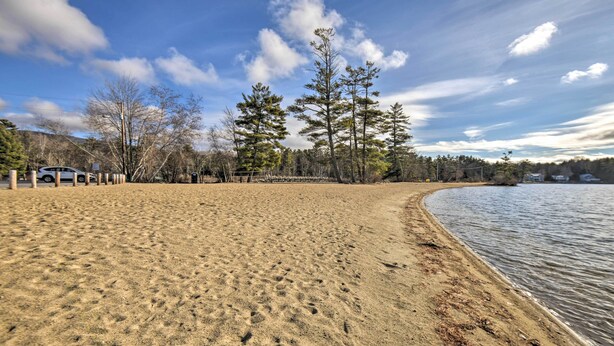 A sandy beach with a clear sky and trees in the background.