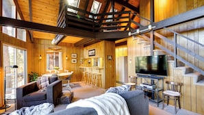 A cozy cabin interior with a living area, dining space, and a staircase. - 3 Mi to Big Trees State Park: Cabin w/ Deck (Arnold)
