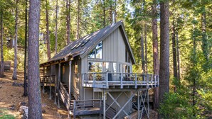A cabin with a deck and stairs, surrounded by tall trees. - 3 Mi to Big Trees State Park: Cabin w/ Deck (Arnold)