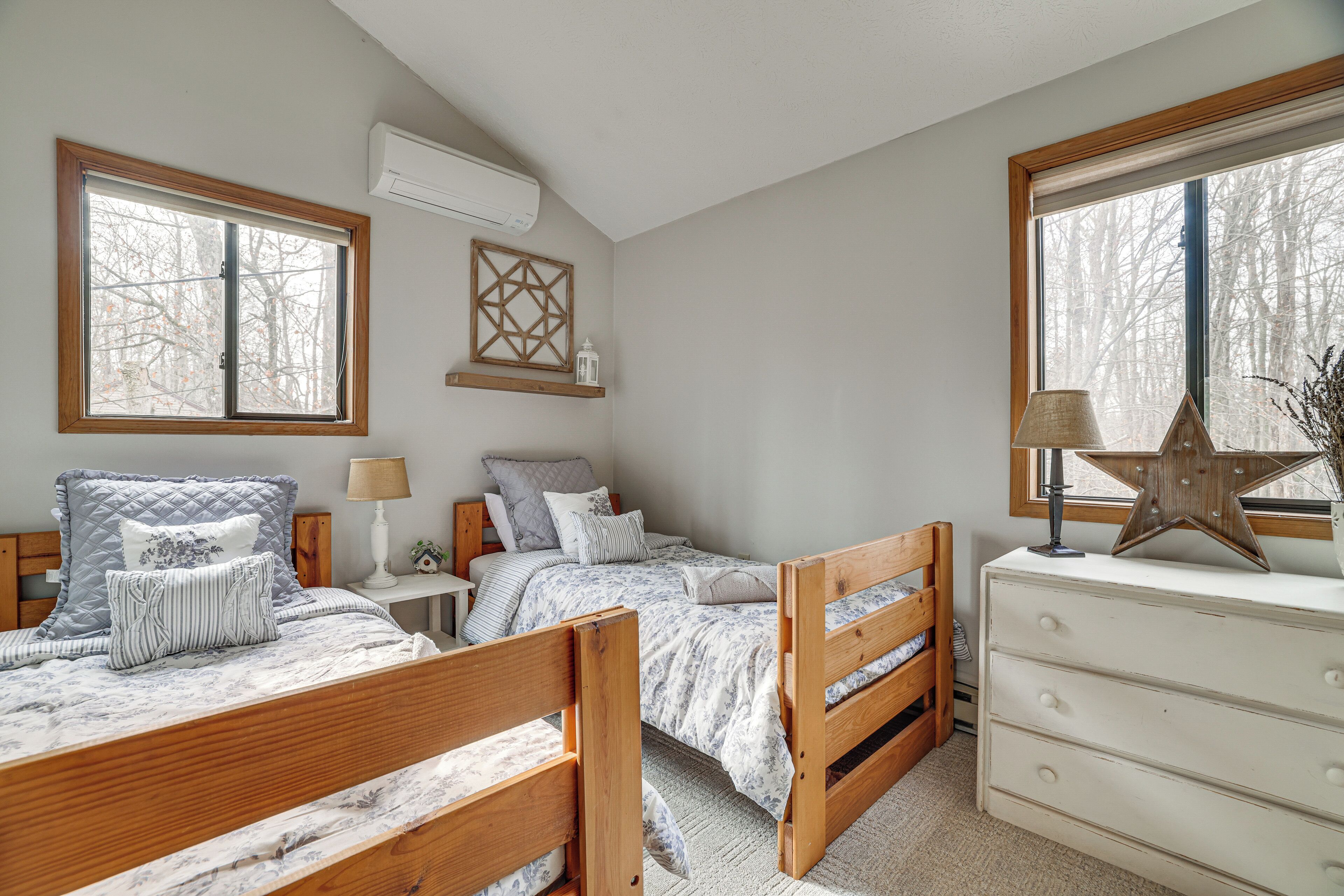 A bedroom with two beds, a dresser, and a window with a star decoration.