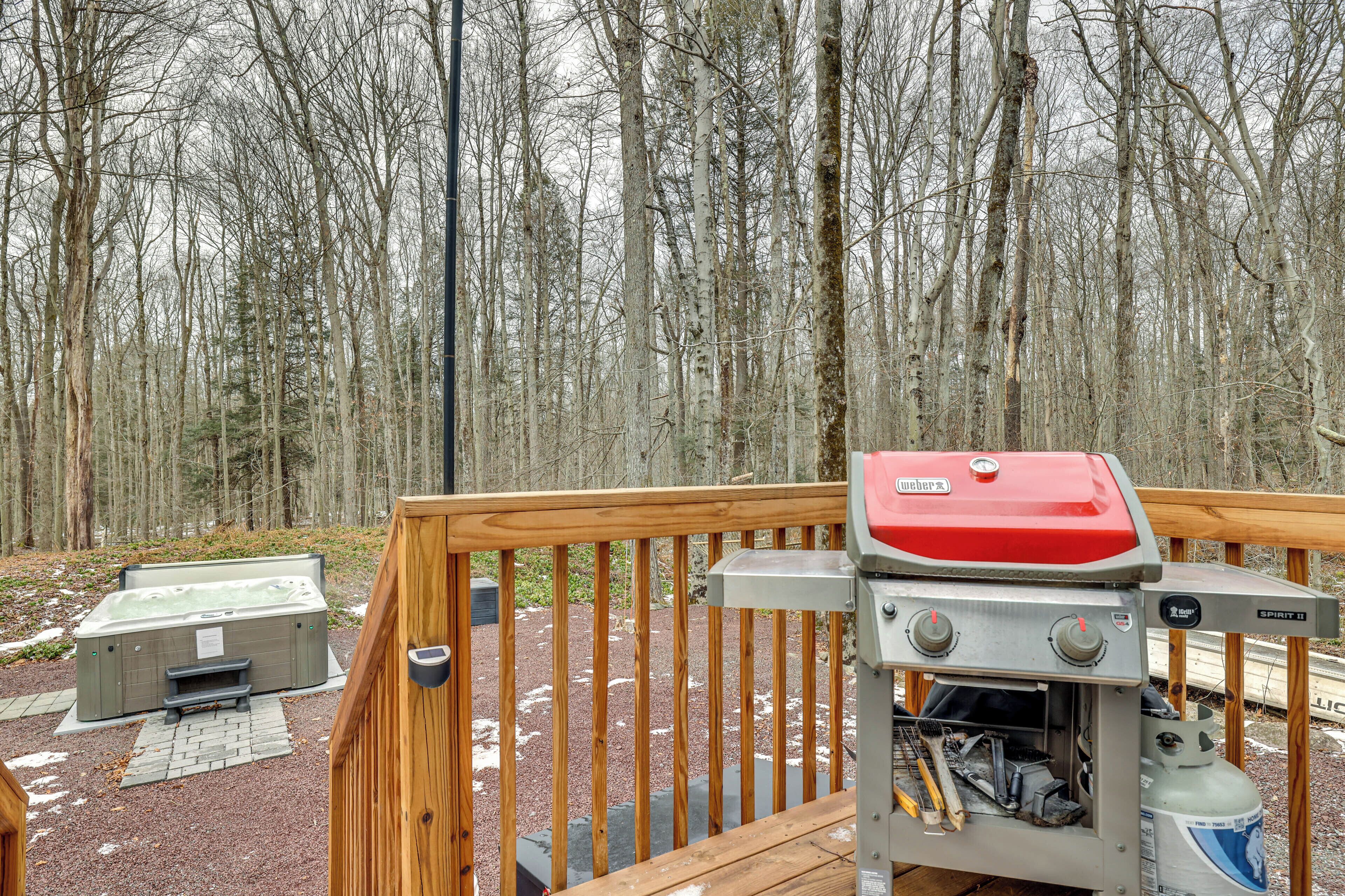 Een terras met een barbecue en een jacuzzi.