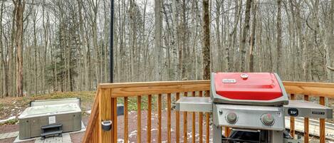 Een terras met een barbecue en een jacuzzi.