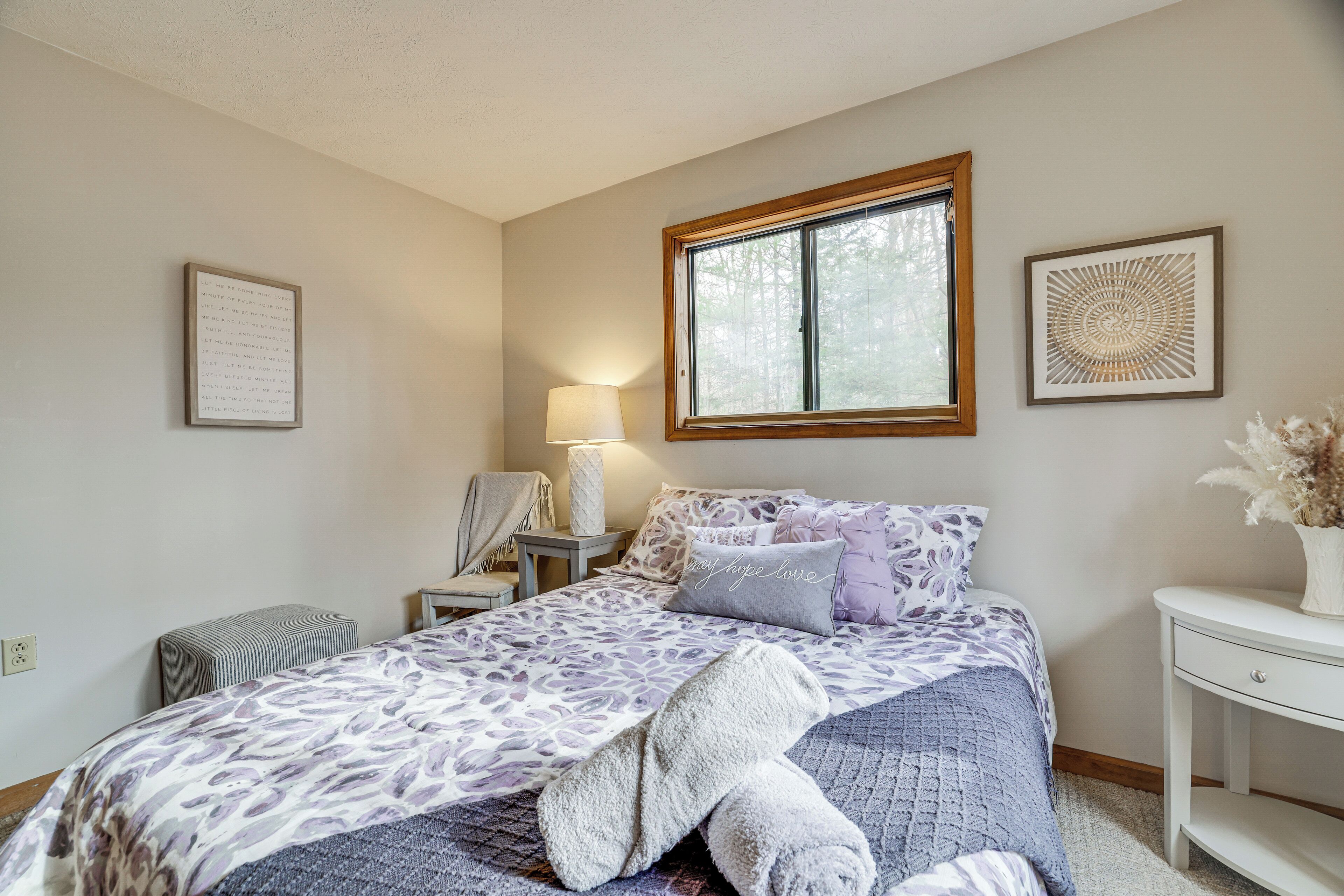 A bedroom with a bed, bedside tables, a window, and wall decorations.