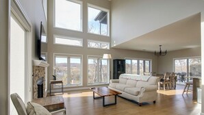 Un salón amplio con chimenea, ventanas grandes, un sofá y una zona de comedor.