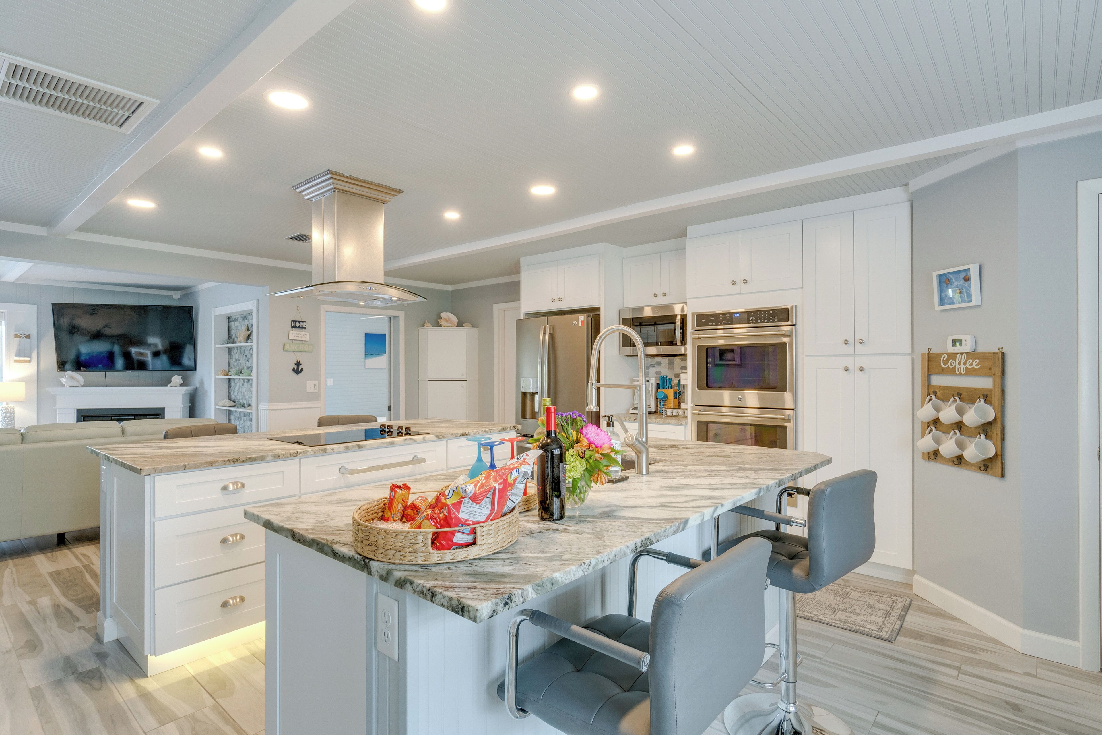 A modern kitchen with white cabinetry, a marble countertop, and stainless steel appliances.