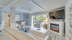 Sala de estar com lareira, ventilador de teto e vista para o exterior.