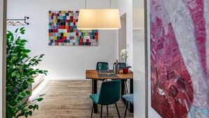 Un comedor moderno con una mesa de madera, sillas azul verdosas y un cuadro abstracto colorido en la pared.