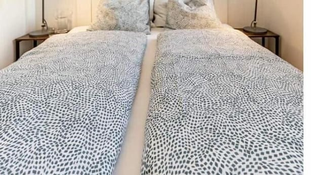 Una cama con una colcha estampada, un cabecero con diseño de ladrillos y dos lámparas de noche.