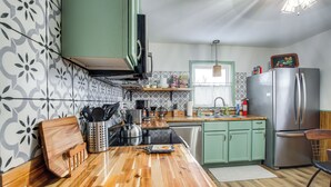 A kitchen with a wooden countertop, green cabinets, a stainless steel refrigerator, and a patterned backsplash. - Pet-friendly Hiawatha Retreat w/ Private Yard! (Hiawatha)