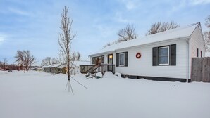 A single-story house with a covered porch, surrounded by snow. - Pet-friendly Hiawatha Retreat w/ Private Yard! (Hiawatha)