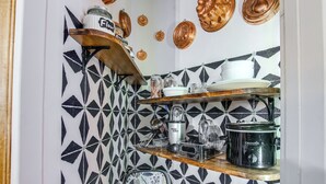 A kitchen with patterned tiles, a wooden shelf with kitchenware, and a crockpot on the counter. - Pet-friendly Hiawatha Retreat w/ Private Yard! (Hiawatha)