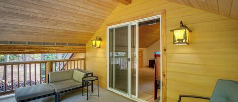 A wooden deck with a bench and a table, a sliding glass door, and two wall-mounted lanterns.