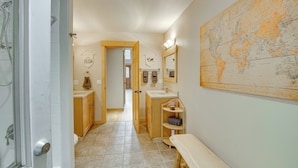 Een badkamer met een grote wereldkaart, houten kastjes, een bankje en een douchegedeelte.
