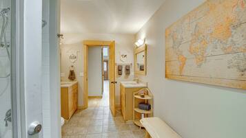Une salle de bain avec une grande carte du monde, des meubles en bois, un banc et un espace douche.