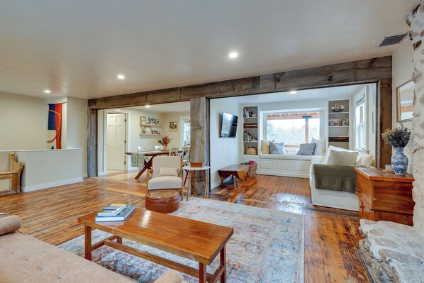 A spacious living room with a wooden coffee table, a sofa, and a dining area with chairs.
