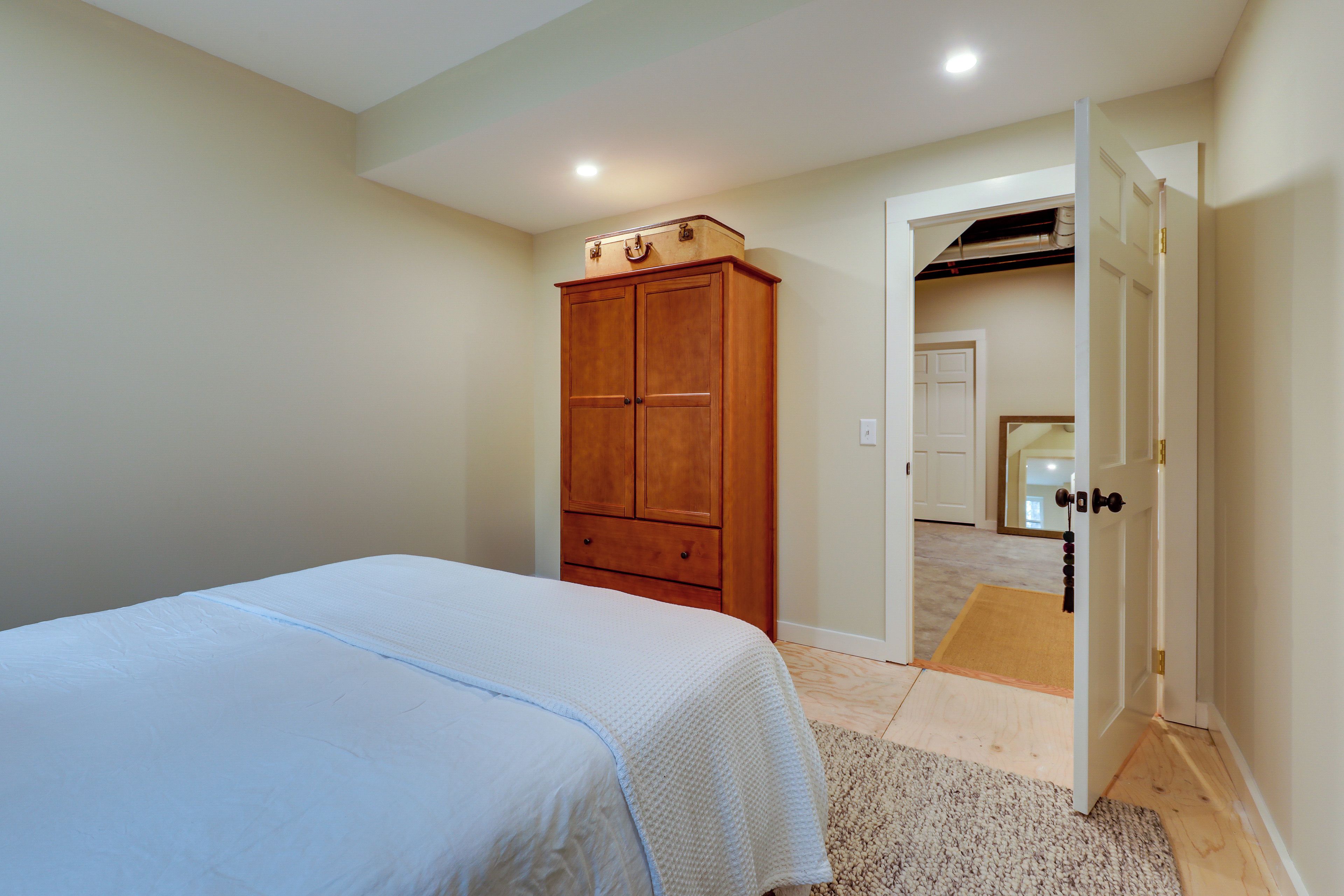 A bedroom with a bed, wooden wardrobe, and an open door leading to another room.