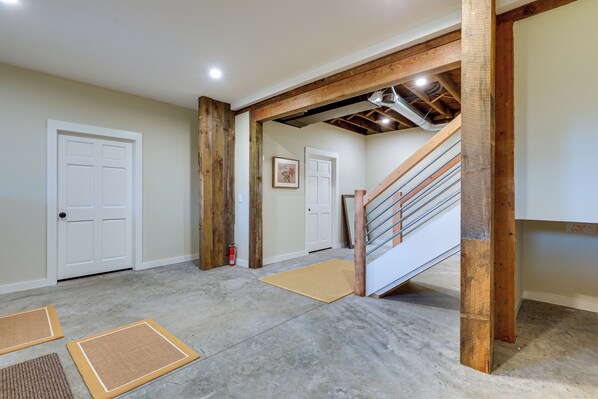 A hallway with a wooden staircase, a fire extinguisher, and two doormats on the floor. - Expansive Wilmot Escape w/ Deck Near Skiing! (Wilmot)