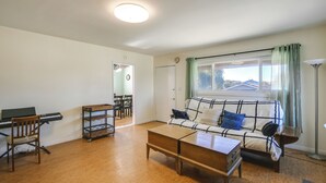Ein Wohnzimmer mit Klavier, Sofa, Couchtisch und einem fenster mit Vorhängen.