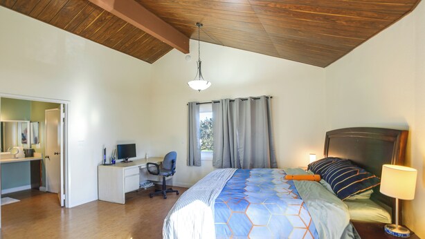 Ein Schlafzimmer mit Bett, Schreibtisch, Stuhl und Lampe.