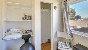 Ein Zimmer mit einem Bett, einem Sessel, einem Kleiderschrank und einem Fenster mit Aussicht.