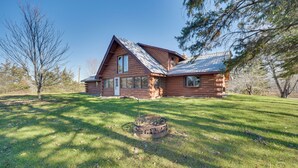 A log cabin with a sloped roof, large windows, and a fire pit in the yard. - Secluded Log Cabin < 1 Mi to Munger State Trail! (Finlayson)
