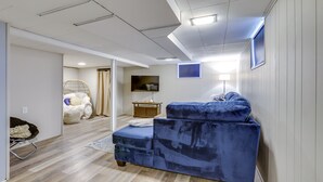 A modern living room with a blue sofa, a television, and a wicker chair. - Charming Arnold Home w/ Patio & Chicken Coop! (Arnold)