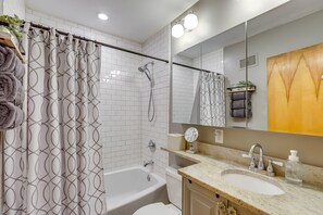 A modern bathroom with a bathtub, shower, and sink.