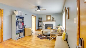 A living room with a fireplace, a ceiling fan, and a bookshelf. - Charming Arnold Home w/ Patio & Chicken Coop! (Arnold)