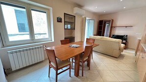 Un coin repas avec une table et des chaises en bois, un canapé et un téléviseur.