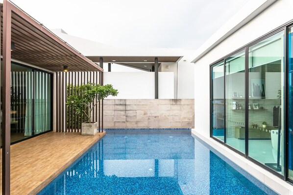 Una piscina interior moderna con un suelo de madera y paredes de vidrio.