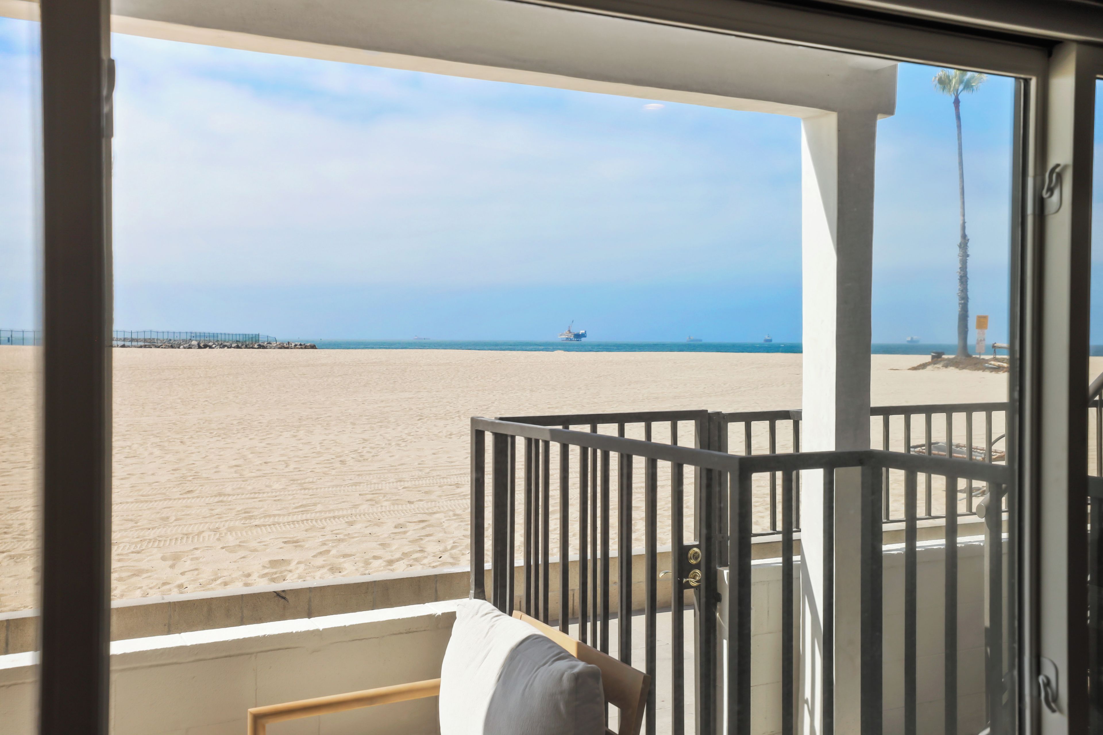 A balcony with a view of a sandy beach and the ocean.