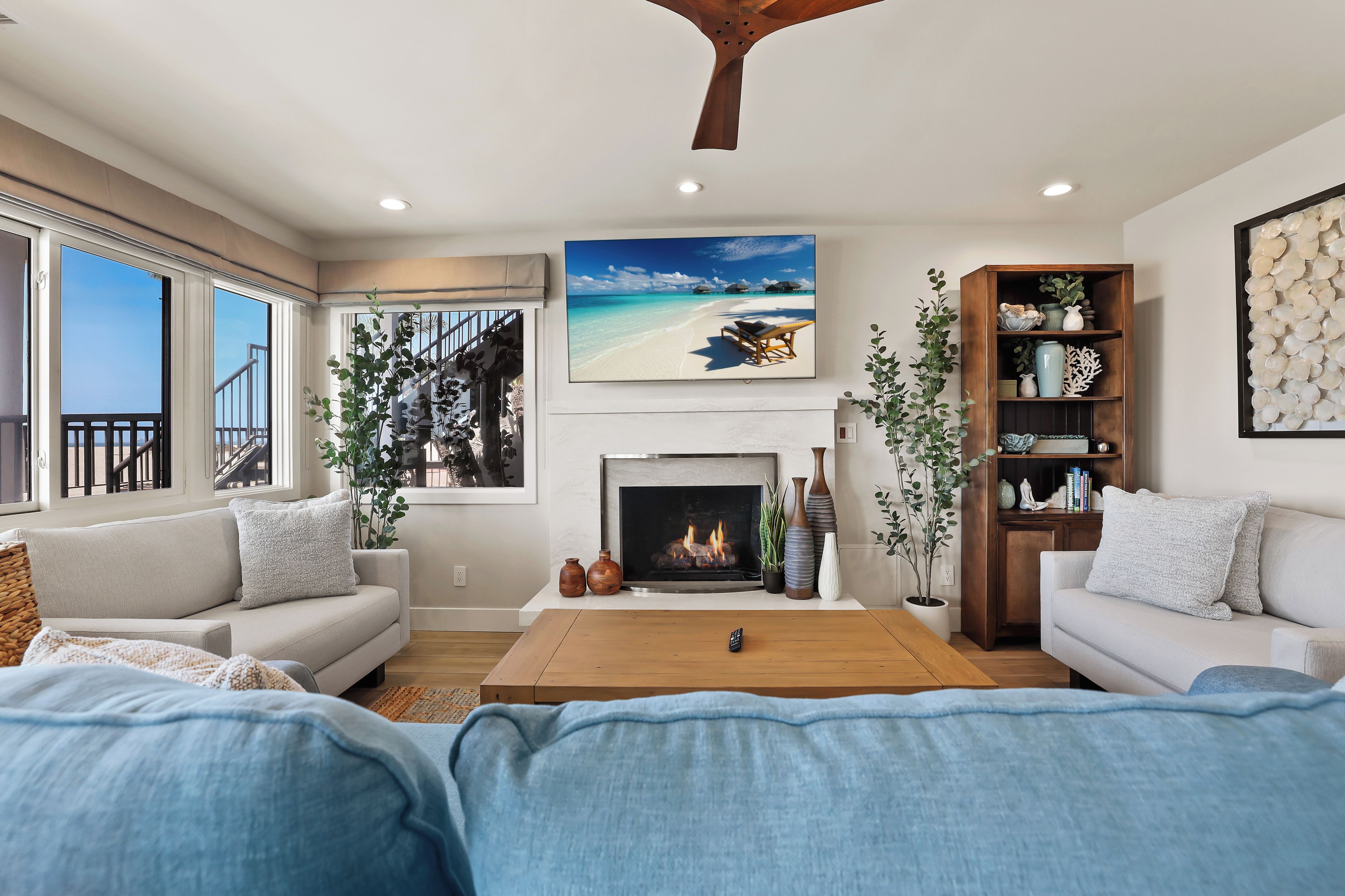 Una sala de estar con chimenea, un ventanal y vista a la playa.
