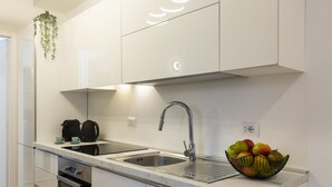 A modern kitchen with white cabinets, a stainless steel sink, and a fruit bowl on the countertop. - notaMi - Little West (Milan)